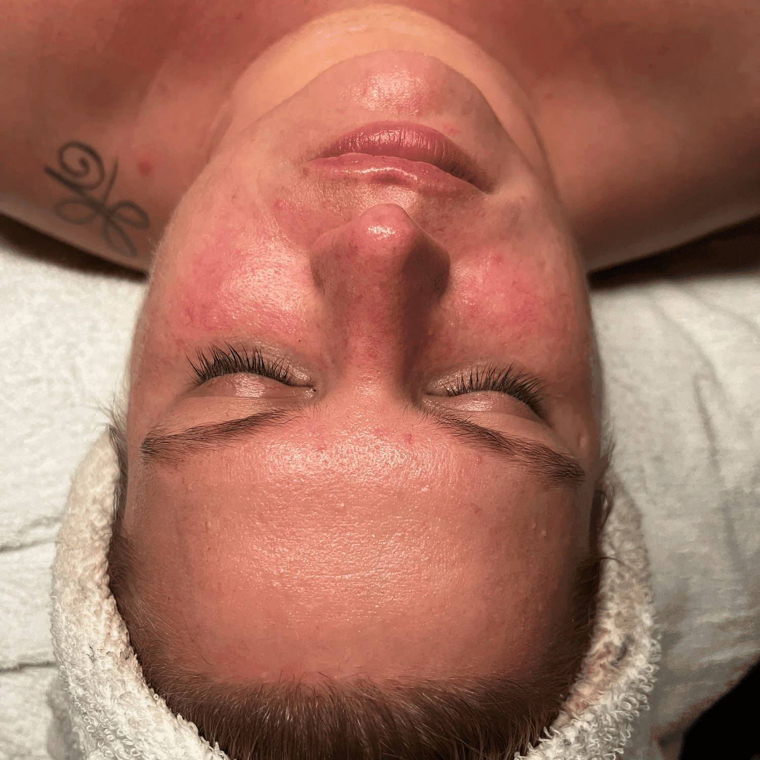 Person with a white headband undergoing a facial treatment, showing a close-up of their face.